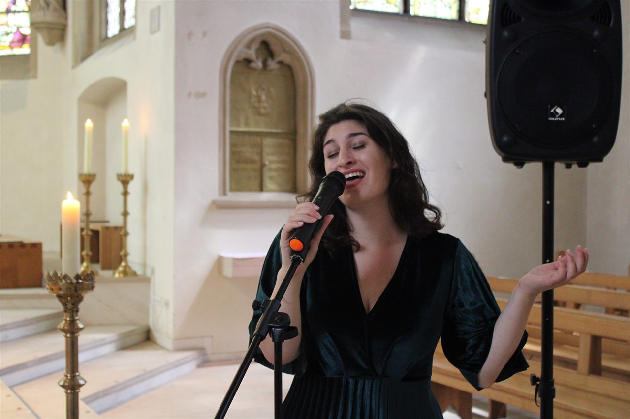 Sophia singt am Mikrofonständer vor dem Altar einer Kirche